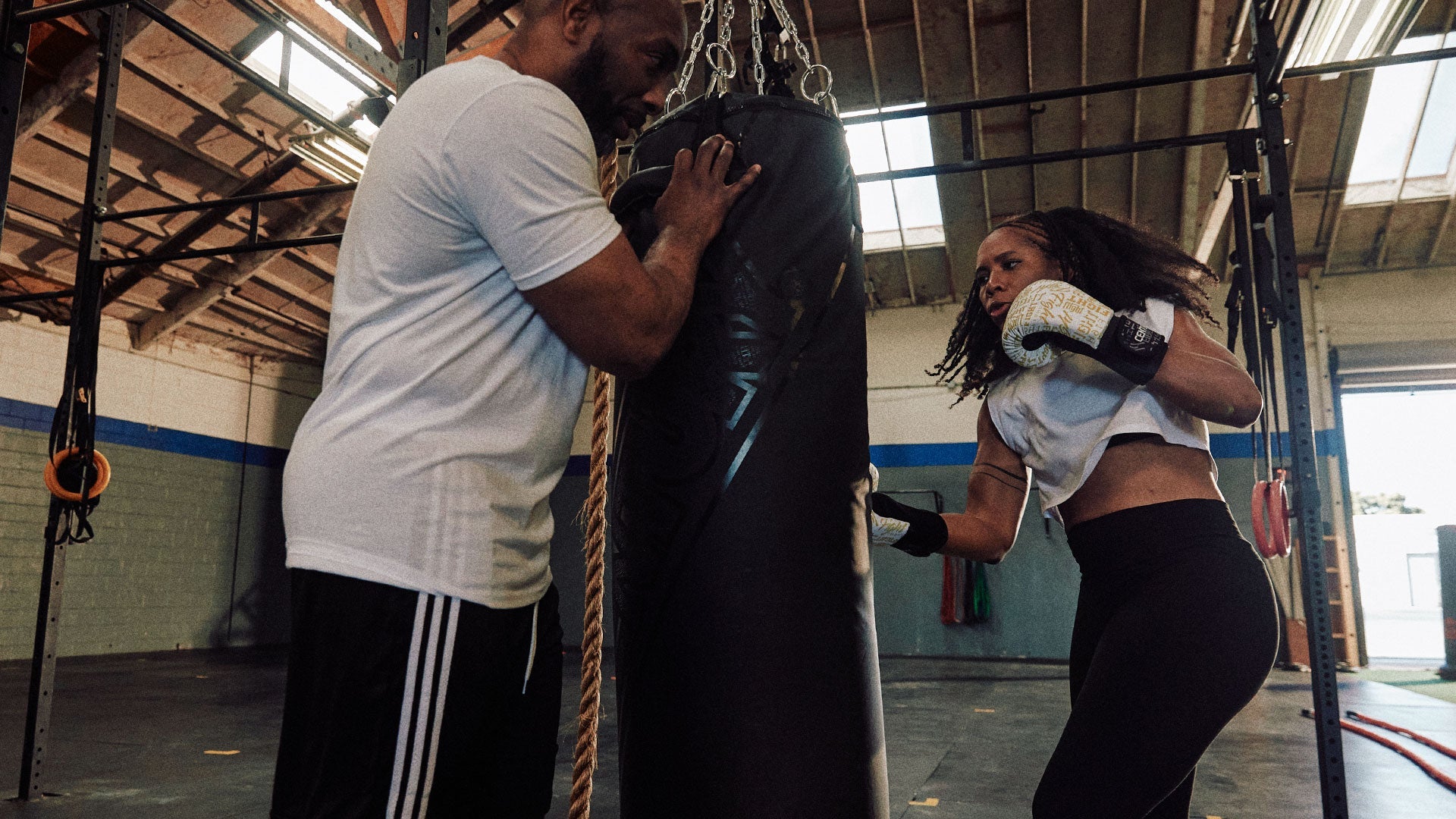 Woman punching bag a man is holding