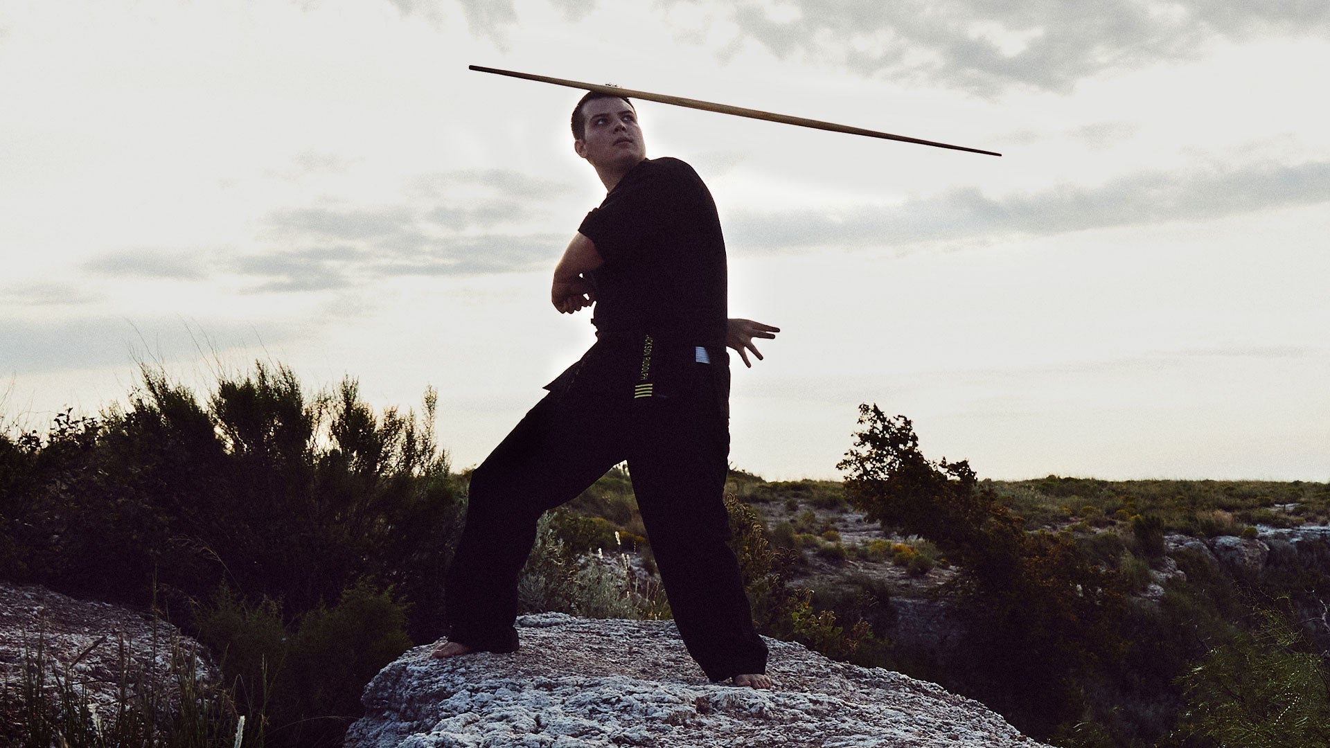 man training in martial arts outdoors with bo staff