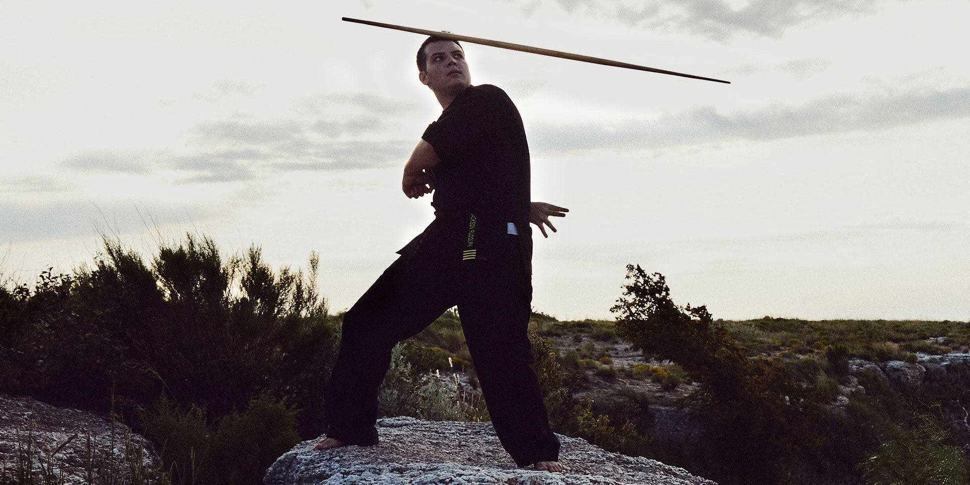 man training in martial arts outdoors with bo staff