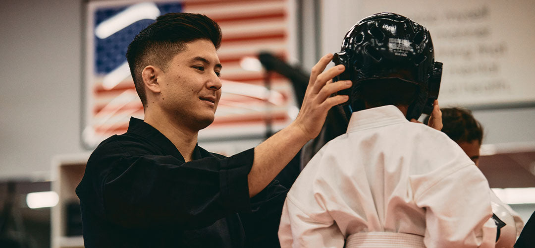 martial artist teacher checking child's protective gear